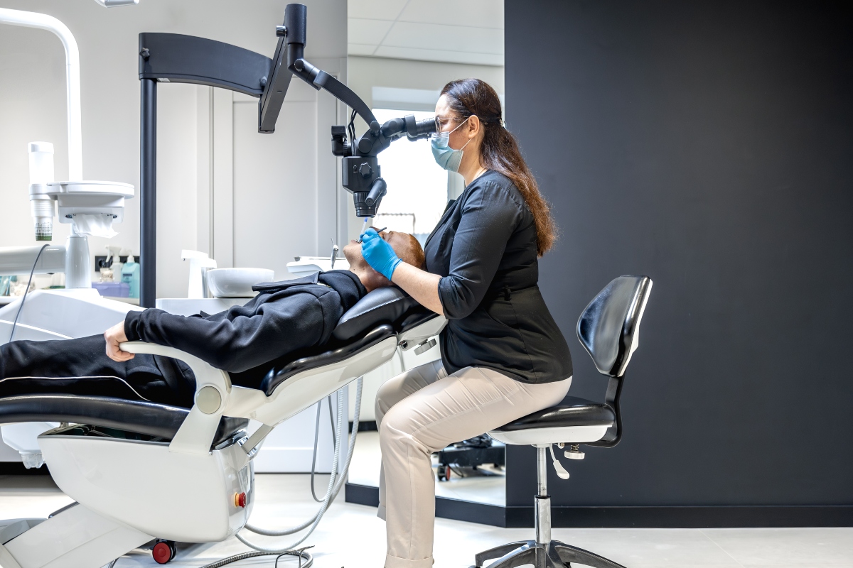 A dentist using specialized equipment to treat a patient.